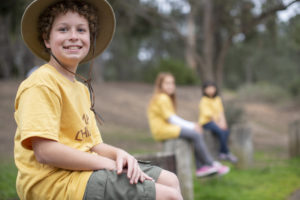 Portrait of a happy boy on fence at summer camp